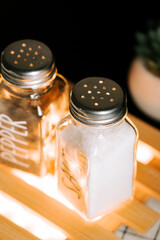 Salt and pepper shakers on a wooden table with soft lighting
