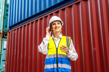 At a bustling container terminal, a young Caucasian businesswoman in safety gear speaks on her phone, organizing shipments and ensuring smooth logistics operations in the vibrant harbor.