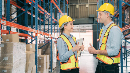 Confidence caucasian man, woman staff worker wear safety helmets, vest show teamwork collaborate, cooperation in logistics inventory operation. show success, efficiency in modern warehouse management.