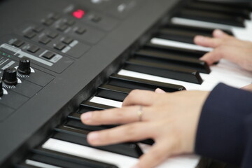 Obraz premium Close-up of Asian hands playing electronic keyboard – music practice and learning