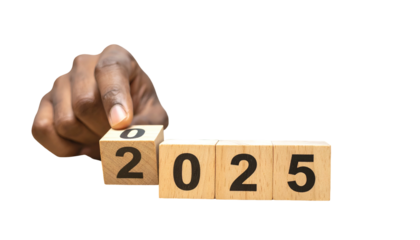 A hand places the zero cube to complete "2025" from wooden blocks on black