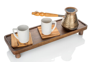 Wooden kitchen table with ceramic cups and a copper cezve, close-up.