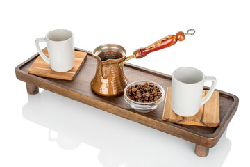 Wooden kitchen table with ceramic cups and a copper cezve, close-up.