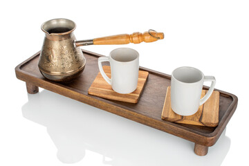 Wooden kitchen table with ceramic cups and a copper cezve, close-up.