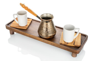 Wooden kitchen table with ceramic cups and a copper cezve, close-up.