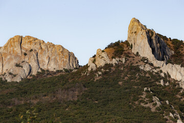 majestic limestone summits under bright blue sky, vivid rocky formations alongside lush greenery in sunlight