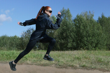 A girl athlete runs lightly in a green forest.