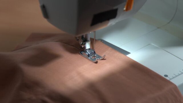 Sewing machine closeup foot sews a stitch on fabric. Machine works video sound.