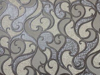 Elegant wallpaper texture featuring a shimmering silver and gray Damask pattern. Ornate, baroque-style scrolls and swirls create a luxurious, neutral background for interior design projects