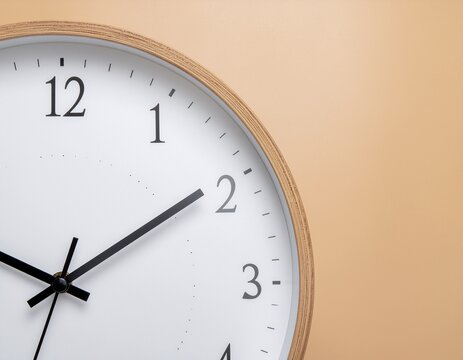 Close up of a simple modern wall clock showing time against a soft background symbolizing punctuality and the passage of time