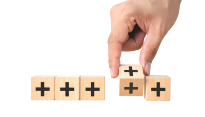 Hand arranging blocks with plus signs. Conceptual image of positivity, growth, and development