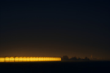 Row of glowing greenhouses in dark rural night landscape, symbolic greenhouse effect and intensive agriculture energy consumption
