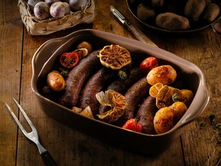 Savor the warmth of traditional Romanian comfort food featuring juicy pork sausages paired with golden potato wedges and aromatic garlic, all beautifully roasted together