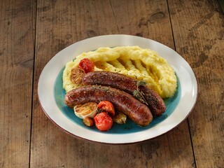 Enjoy a traditional Romanian dish featuring rich pork sausages alongside creamy mashed potatoes and oven-roasted garlic, perfect for a warming winter meal with family
