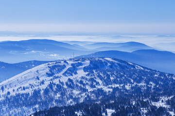 Aerial view of mountain ridges in soft fog and sky. Beautiful white blue peaks Altay mountains fades in distance. Minimal Nature abstract photo, natural winter picturesque scene, panoramic skyline.