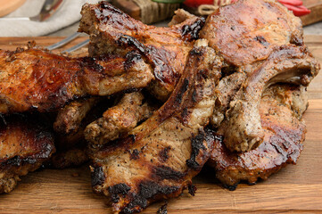 A pile of freshly grilled pork ribs with the bones resting on a wooden cutting board.