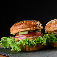 A delicious homemade burger with a juicy patty, cheese, tomato, red onion, cucumber and crispy lettuce