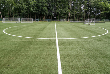 Weitwinkel Blick auf den Mittelkreis eines Fußballplatzes mit Toren und mit Kunstrasen dessen...