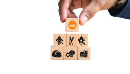 Hand placing safety helmet block atop a pyramid of construction-related wooden blocks