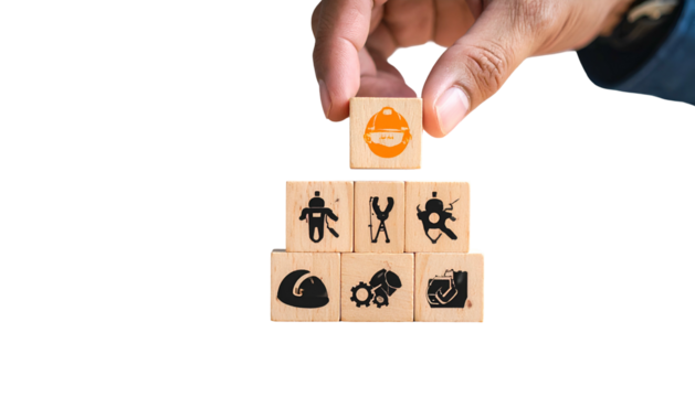 Hand placing safety helmet block atop a pyramid of construction-related wooden blocks - Powered by Adobe
