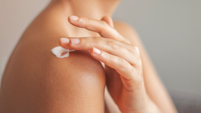 Woman applying body cream on arm, beauty skin care concept