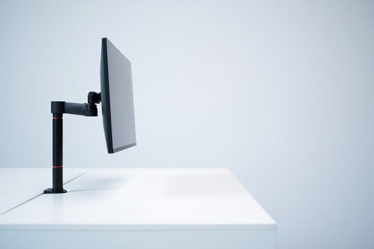 Side View of Computer Monitor on Desk Mount Arm over White Table Showing Clean Office Setup Workspace with Copy Space 149