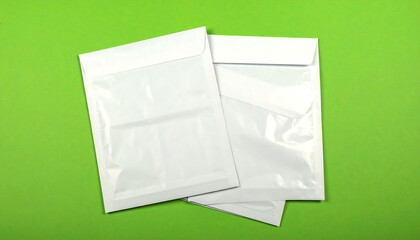 Two white plastic envelopes stacked on a vibrant green background, ready for mail and packaging concepts, offering a clean and minimalist look.