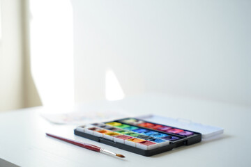 Watercolor Palette with Colorful Paints and Brush Close Up Artistic Tool for Painting Hobby Creative Expression Art Supplies on White Surface