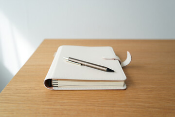 Closed Journal on Wooden Desk with Ballpoint Pen for Writing, Reflection, Planning and Organization in Simple and Minimalist Style