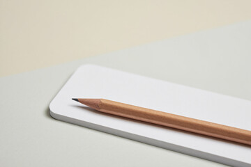 Minimalist Composition of Pencil Resting on White Pad Closeup of light brown pencil on white pad minimalist design home office equipment flat lay
