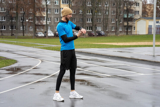 Runner checking smartwatch on a wet outdoor track