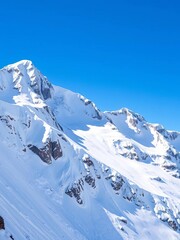 Powdery snow cascades down a majestic mountain peak under a clear blue sky, beckoning adventure,  ideal,  top