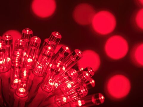 Closeup of a cluster of bright red led string lights creating a beautiful bokeh effect in the dark background for a festive atmosphere