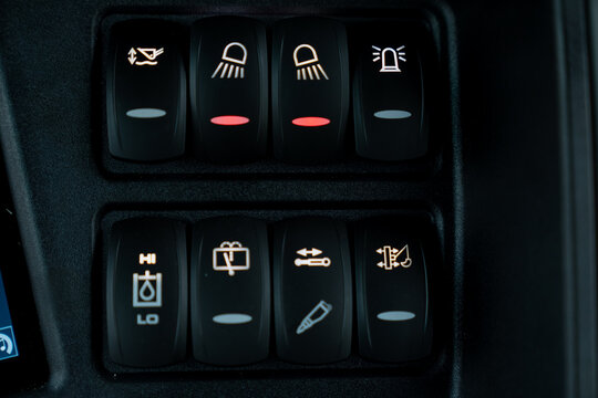 Detailed view of construction equipment switch panel featuring headlight controls, hydraulic function selectors and operational system buttons designed for industrial vehicle operation