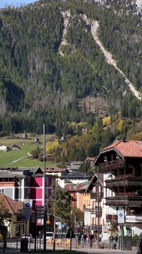 A picturesque view of Moena, Italy, showcasing the charming village streets with colorful buildings and a stunning mountain backdrop, capturing the essence of alpine village life.