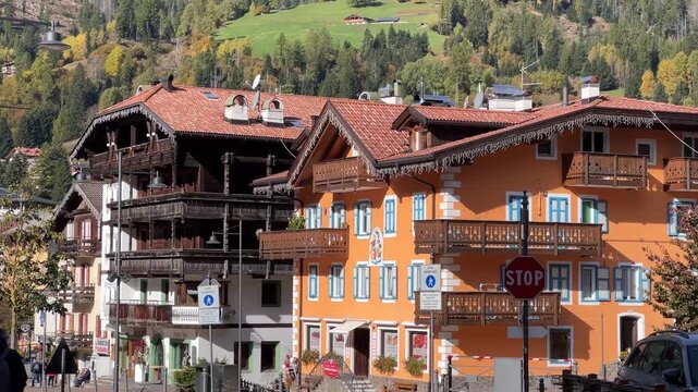 A picturesque view of Moena, Italy, showcasing the charming village streets with colorful buildings and a stunning mountain backdrop, capturing the essence of alpine village life.