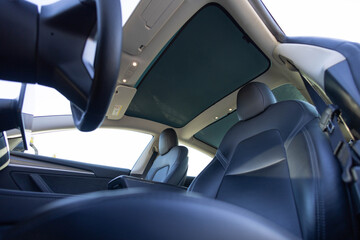 Sunroof hatch with tinted glass. Automotive sunroof. Hatch in car roof. Panoramic glass sun roof in the new electric car. Clean glass and view from inside to the sky