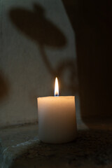 Single Burning Candle with Soft Shadow on Stone Surface in Quiet Low-Light Setting