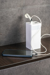 A sleek, modern power bank charging a smartphone on a stylish wooden surface, showcasing contemporary technology and minimalist design