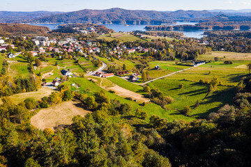 Wide aerial panorama of Polańczyk village and the Solina Lake (Jezioro Solińskie) in Bieszczady, Poland. Scenic October landscape with dam structure in the background.