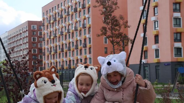 Three little triplet sisters ride on a round swing in autumn