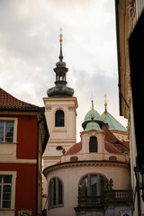 Fototapeta premium Prague church towers with copper domes, historic architecture in old town, baroque and gothic spires against cloudy sky, Czech Republic religious buildings