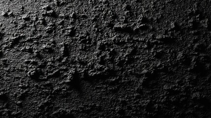 A close-up of a rough, dark textured surface that appears almost abstract. The shadows and light create depth in this black backdrop.