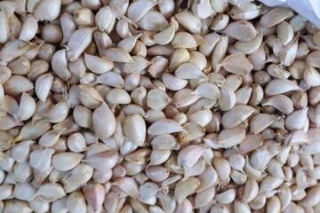 A high-angle, close-up shot showing a large, textured pile of individual, peeled and unpeeled...