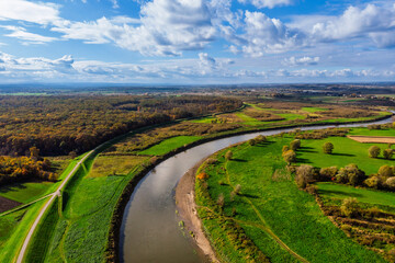 Wide aerial drone view of the Vistula River (Wisła) near Ispina village, Krakow area, Poland. Scenic landscape featuring flood embankments, rural houses, and a cycling route.