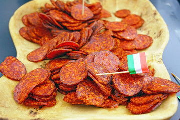 Salami slices on a wooden plate with a small Hungarian flag. Represents traditional regional cuisine, national food identity, rustic meat presentation, culinary heritage mood, and authentic gastronomy