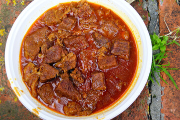 Close-up of finished beef goulash with tender meat chunks in glossy red sauce served in white bowl. Represents comfort food, Hungarian stew presentation, traditional meat dish, and warming winter food