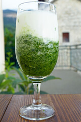 Layered smoothie with greens and yogurt in an elegant stemmed glass. Represents healthy drink, cucumber herb blend, probiotic beverage combination, wellness drink styling, and nutritious refreshment.