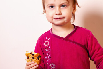 Girl with a calm expression holding a bitten treat. Copy space.