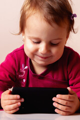 Girl holding a tablet while smiling warmly at the camera.